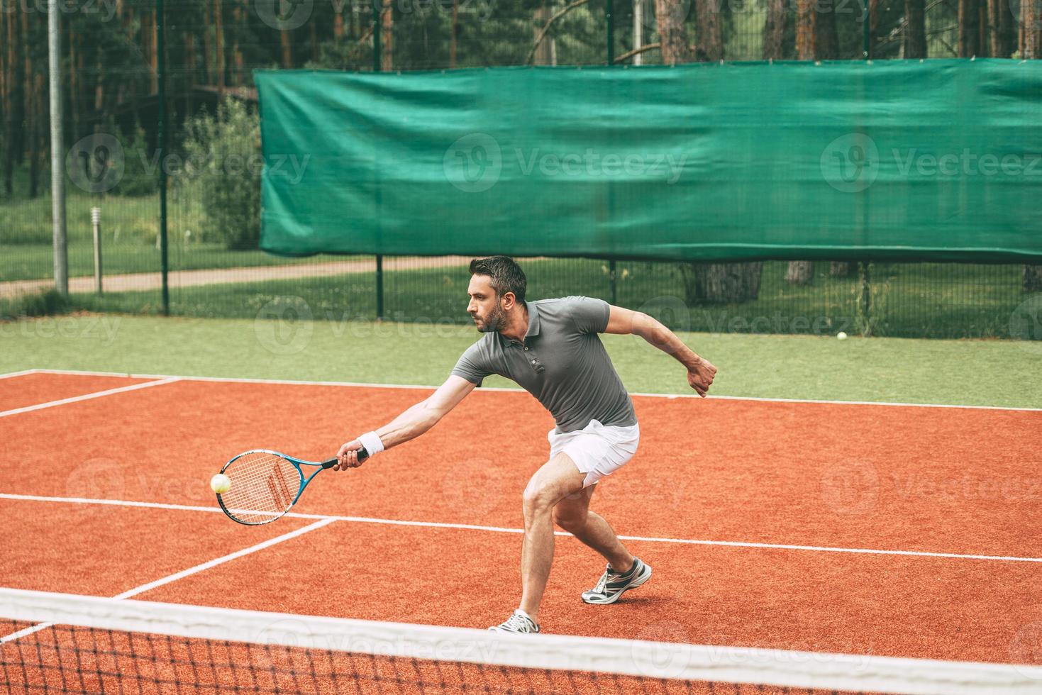 giocando tennis. fiducioso giovane uomo nel gli sport Abiti giocando tennis su tennis Tribunale foto