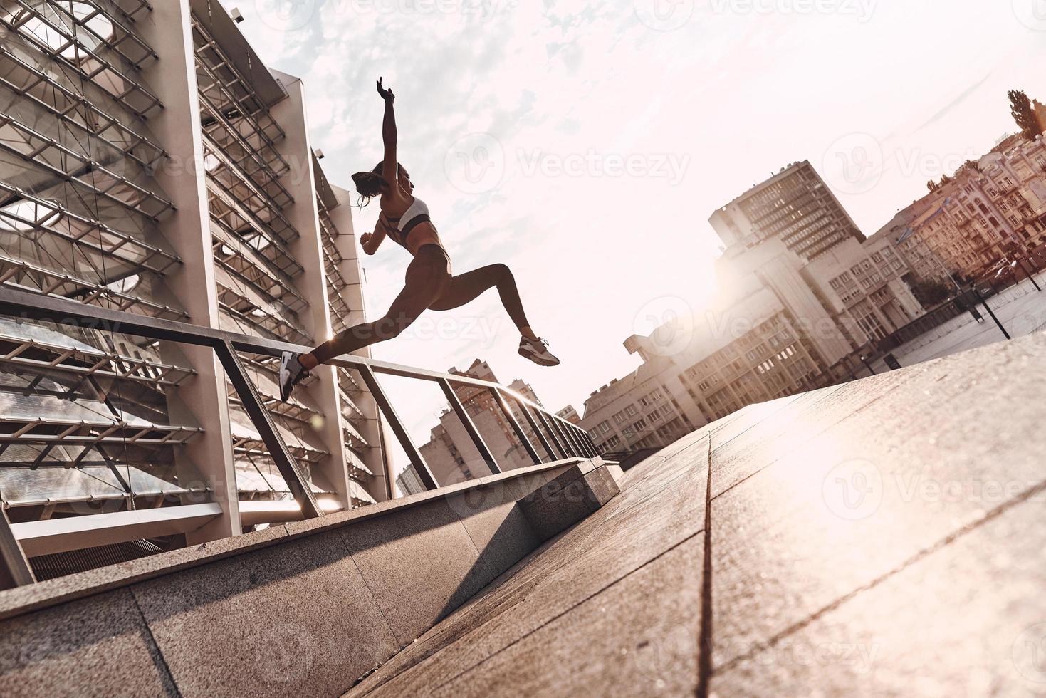 appena volare. pieno lunghezza di moderno giovane donna nel gli sport capi di abbigliamento salto mentre esercizio all'aperto foto