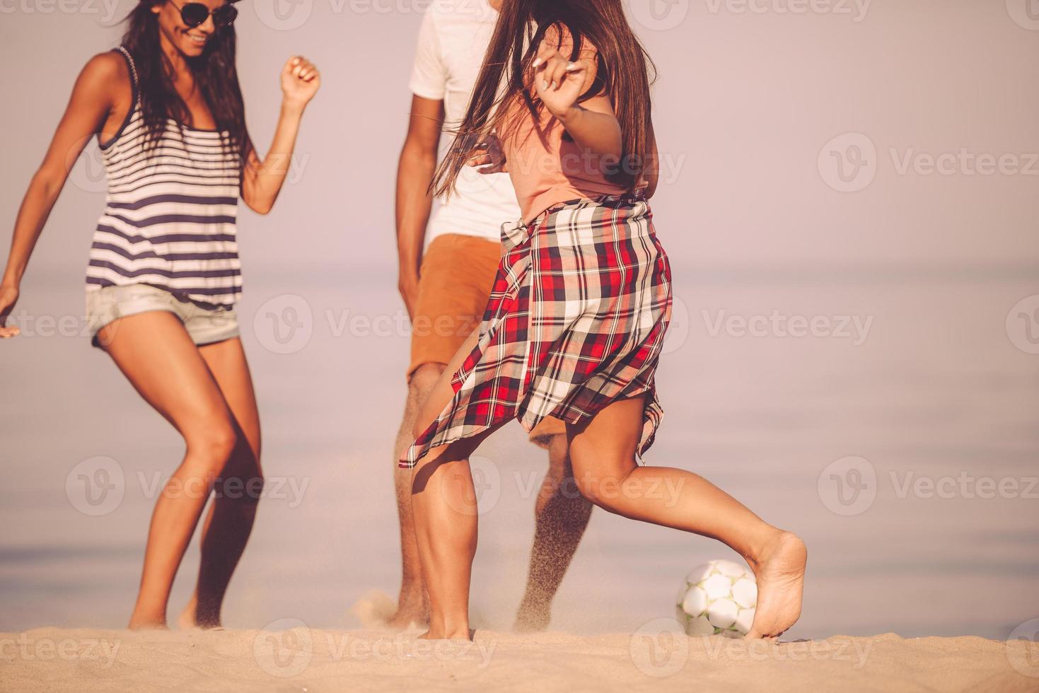 spiaggia palla divertimento. ritagliata Immagine di allegro giovane persone giocando con calcio palla su il spiaggia con mare nel il sfondo foto