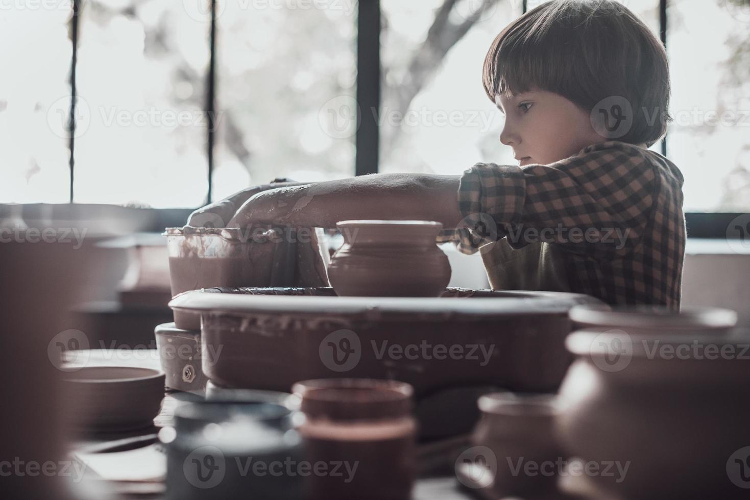 bambino su ceramica classe. fiducioso poco ragazzo fabbricazione ceramica pentola su il ceramica classe foto