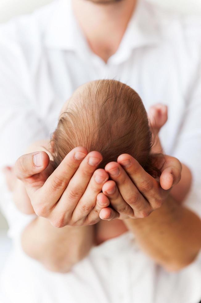 bambino nel padri mani. avvicinamento di maschio mani Tenere foto