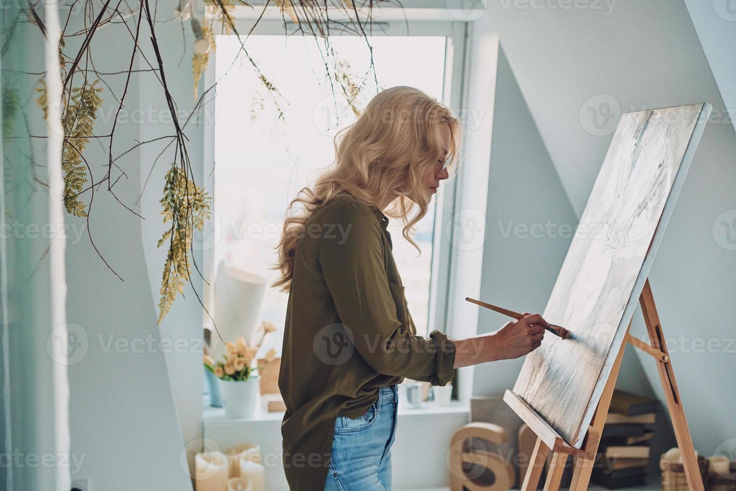 lato Visualizza di attraente giovane donna pittura nel arte studio foto