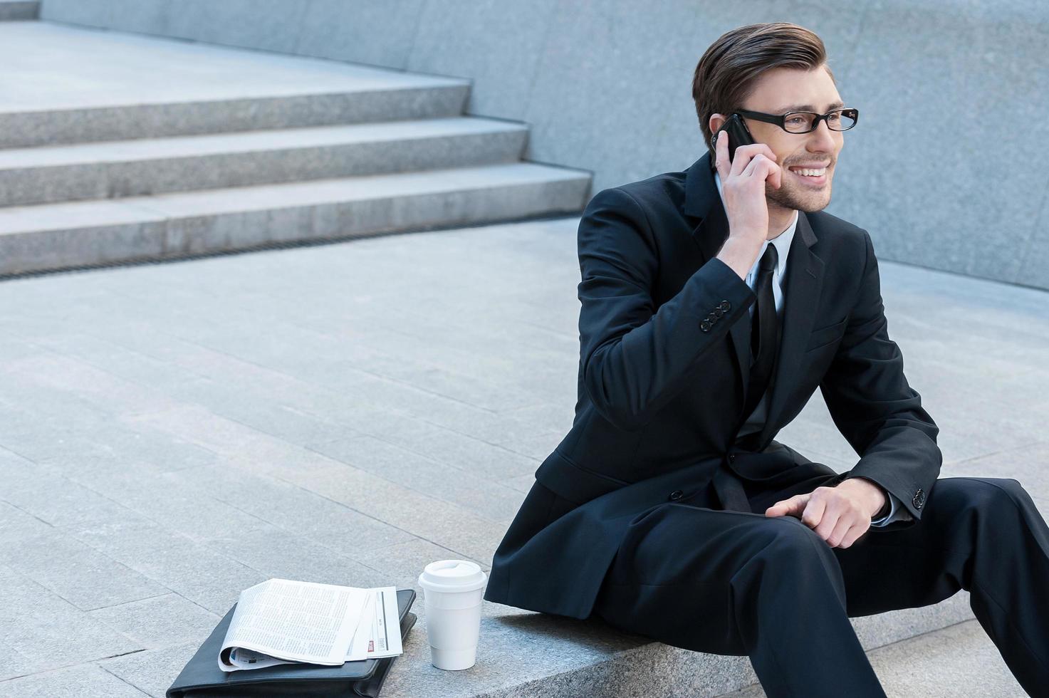 su il Telefono. riuscito uomo d'affari parlando con mobile Telefono mentre seduta su le scale foto