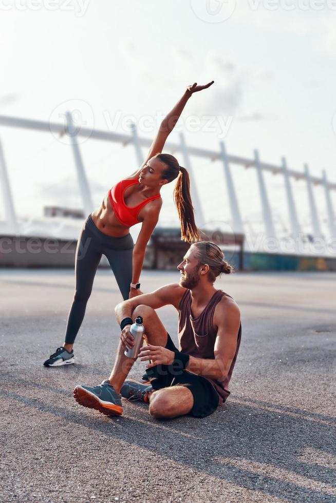 giovane uomo e donna nel gli sport capi di abbigliamento riscaldamento su e allungamento all'aperto foto