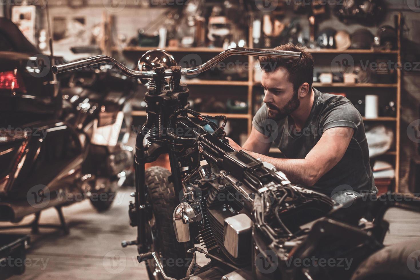 meccanico a opera. fiducioso giovane uomo riparazione motociclo nel riparazione negozio foto