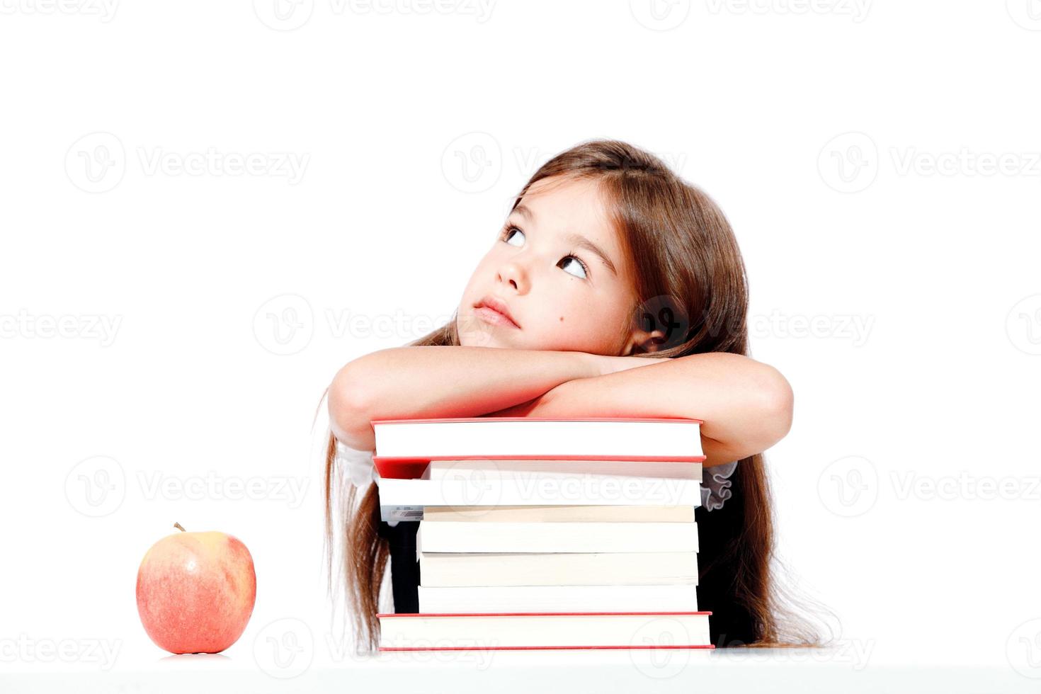 carino poco bambino ragazza guardare su su il scrivania a scuola. foto