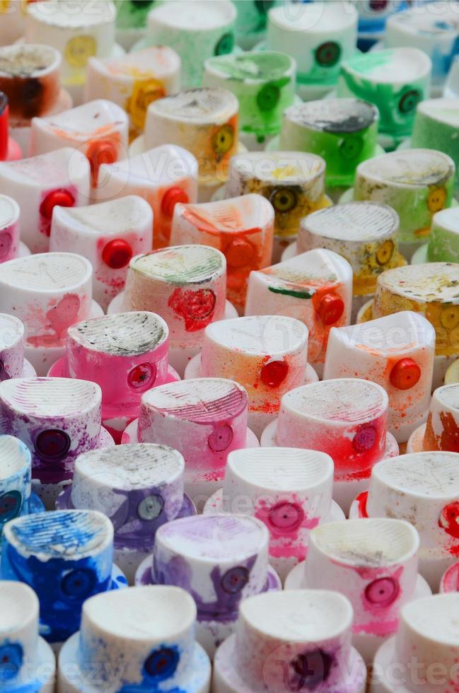 un' modello a partire dal un' molti ugelli a partire dal un' dipingere spruzzatore per disegno graffiti, spalmato in diverso colori. il plastica caps siamo disposte nel molti righe formatura il colore di il arcobaleno foto