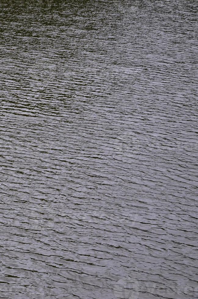 il struttura di buio fiume acqua sotto il influenza di vento, impresso nel prospettiva. verticale Immagine foto