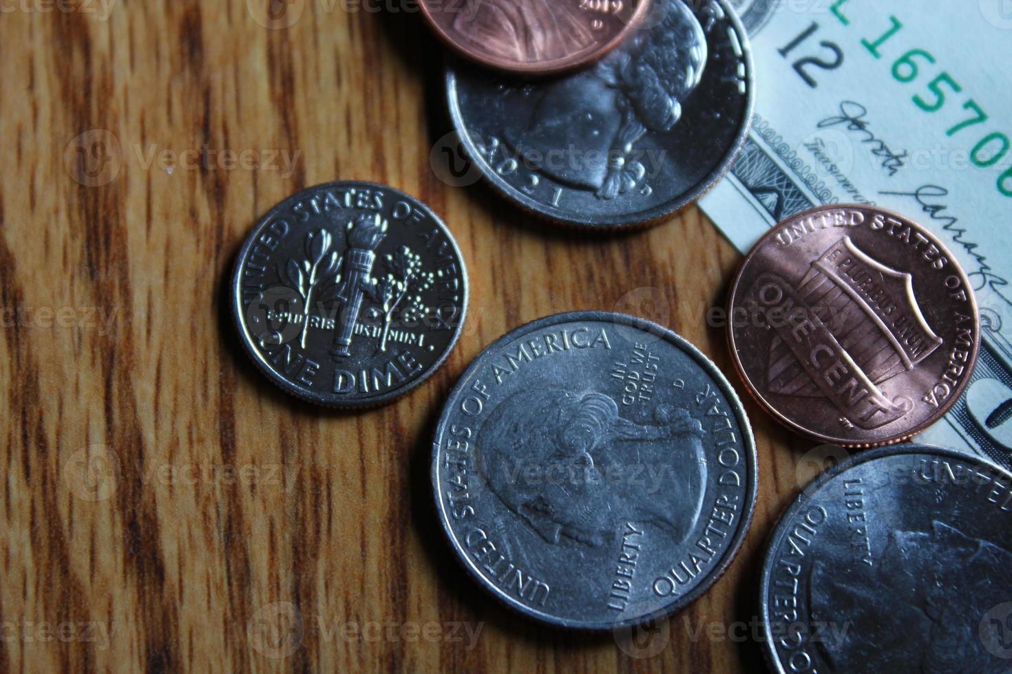 dollaro monete e dollaro fatture sparpagliato su un' di legno tavolo, piatto posare dollaro monete. foto