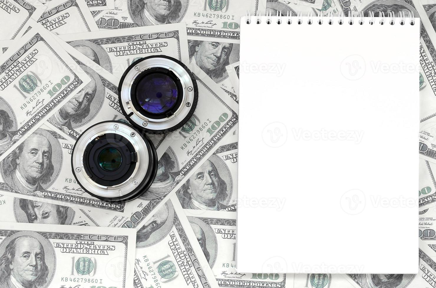 Due fotografico lenti a contatto e bianca taccuino menzogna su il sfondo di un' lotto di dollaro fatture. spazio per testo foto