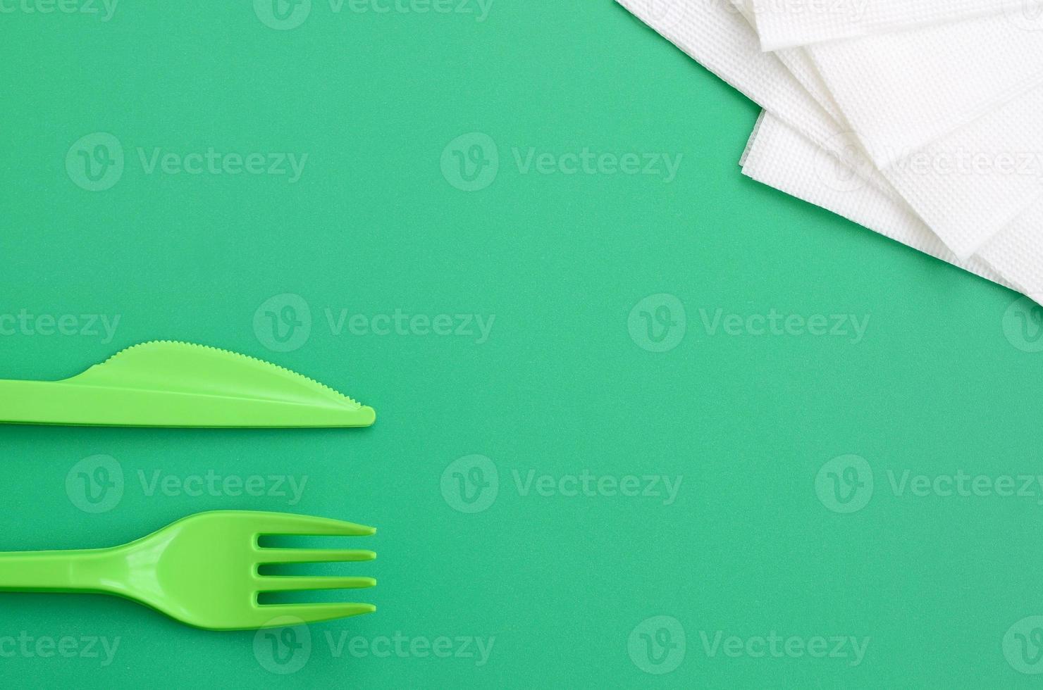 monouso plastica posate verde. plastica forchetta e coltello menzogna su un' verde sfondo superficie Il prossimo per tovaglioli foto