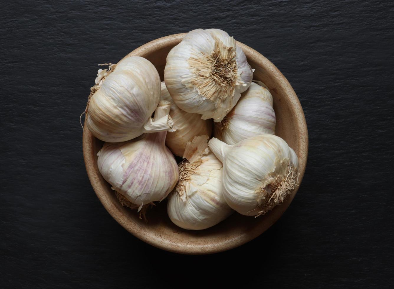 teste d'aglio in una ciotola di legno foto