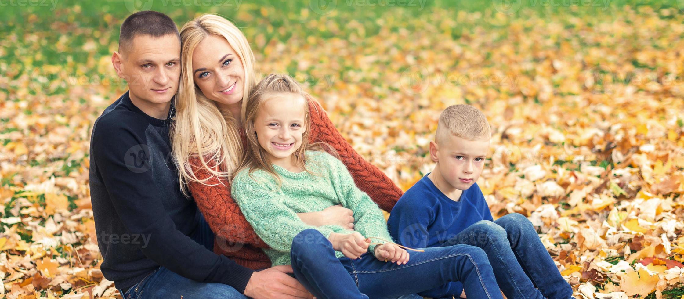 ritratto di giovane famiglia seduta nel autunno le foglie foto