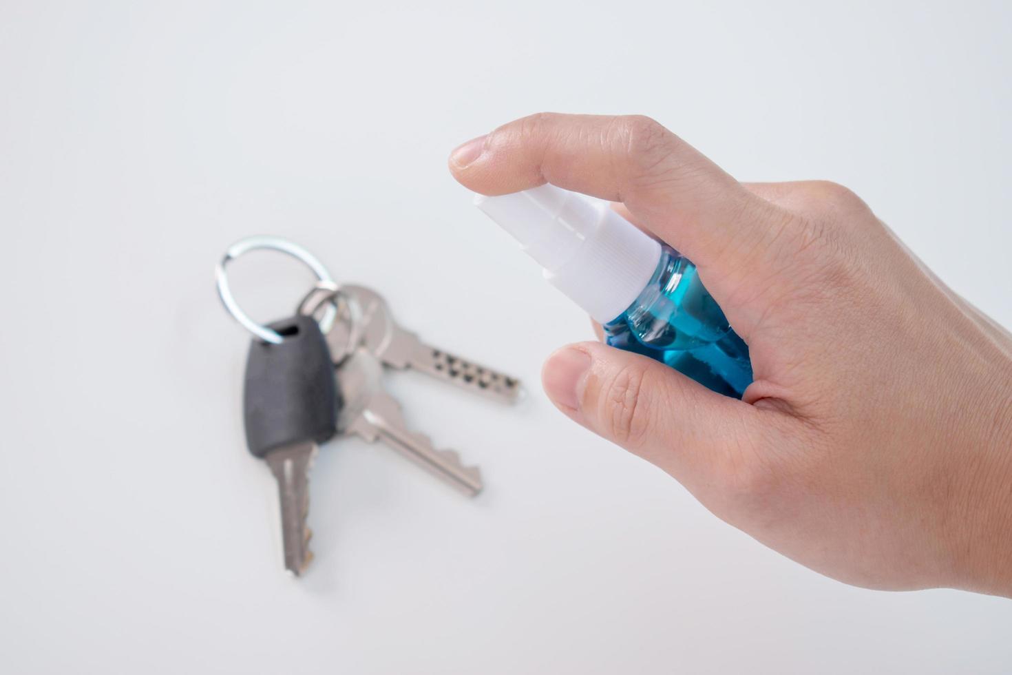 vicino su di il mano con un' spray di alcool su il chiave per pulire. anti virus concetto. foto