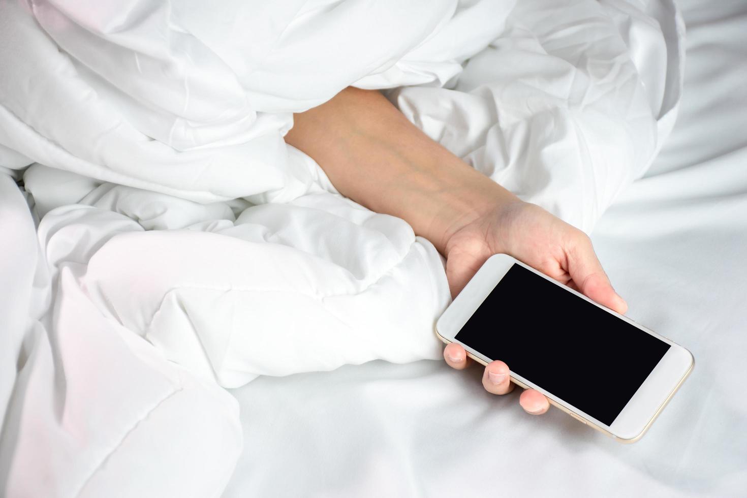 donna addormentato nel letto e Tenere un' smartphone nel mano. foto