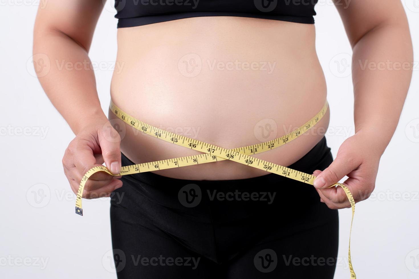 Grasso donne o sovrappeso donne misurare sua pancia Grasso su un' grigio sfondo. foto