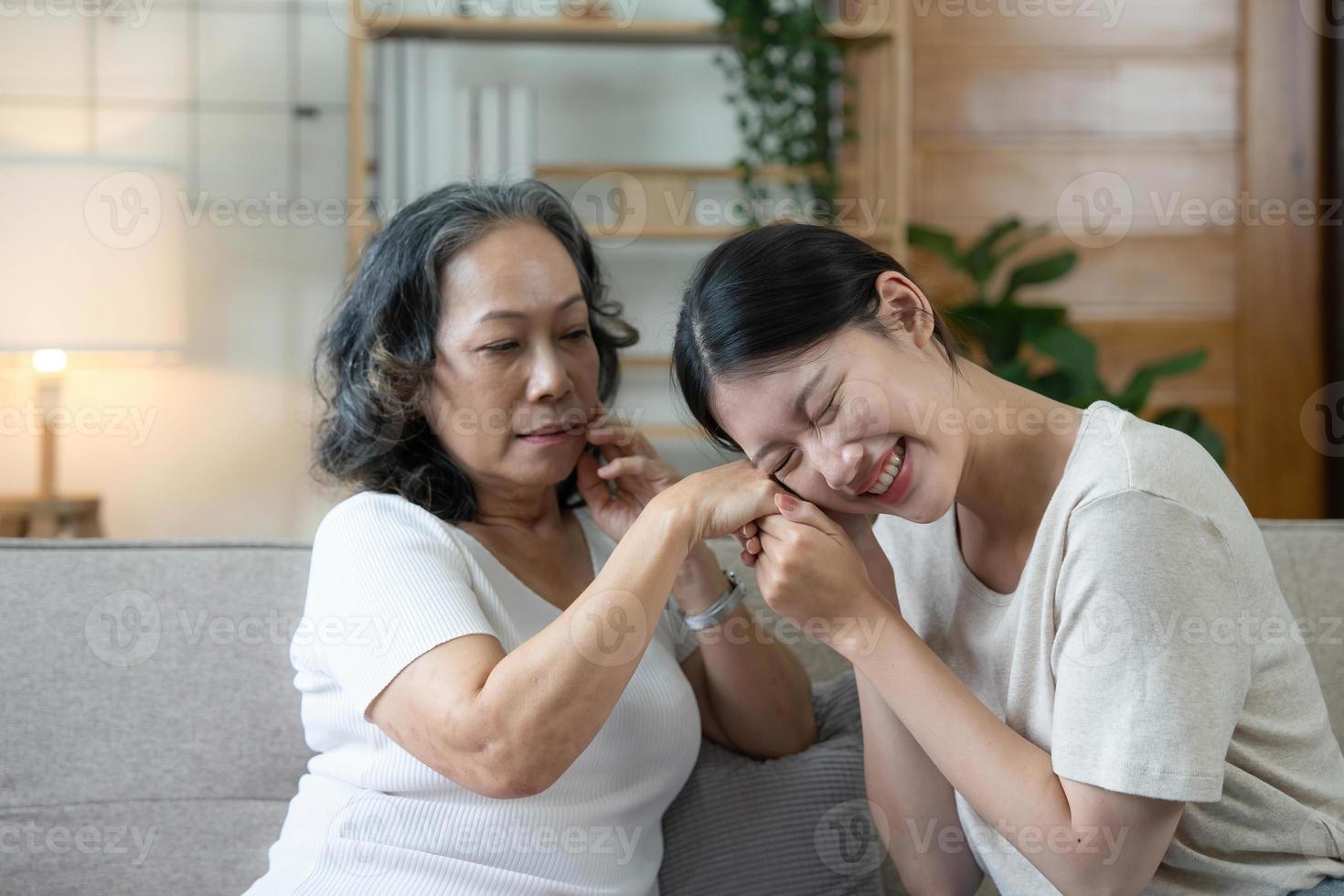 contento adulto nipotina e anziano nonna avendo divertimento godendo parlare sedersi su divano nel moderno vivente camera, sorridente vecchio madre abbracciare giovane cresciuto figlia bonding chat rilassante a casa insieme foto