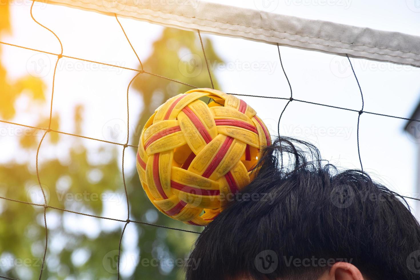 giovane sud-est asiatico maschio sepak takraw giocatore utilizzando il suo giusto mano per hold palla su il suo testa, all'aperto sepak takraw giocando dopo scuola, morbido e selettivo messa a fuoco su sfera. foto