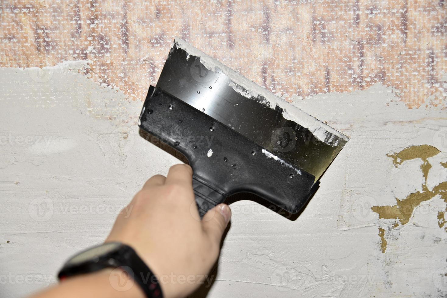 opera con un ferro spatola quando intonacatura il parete con un' cemento soluzione. riparazione di il parete con un' cazzuola con cemento. foto