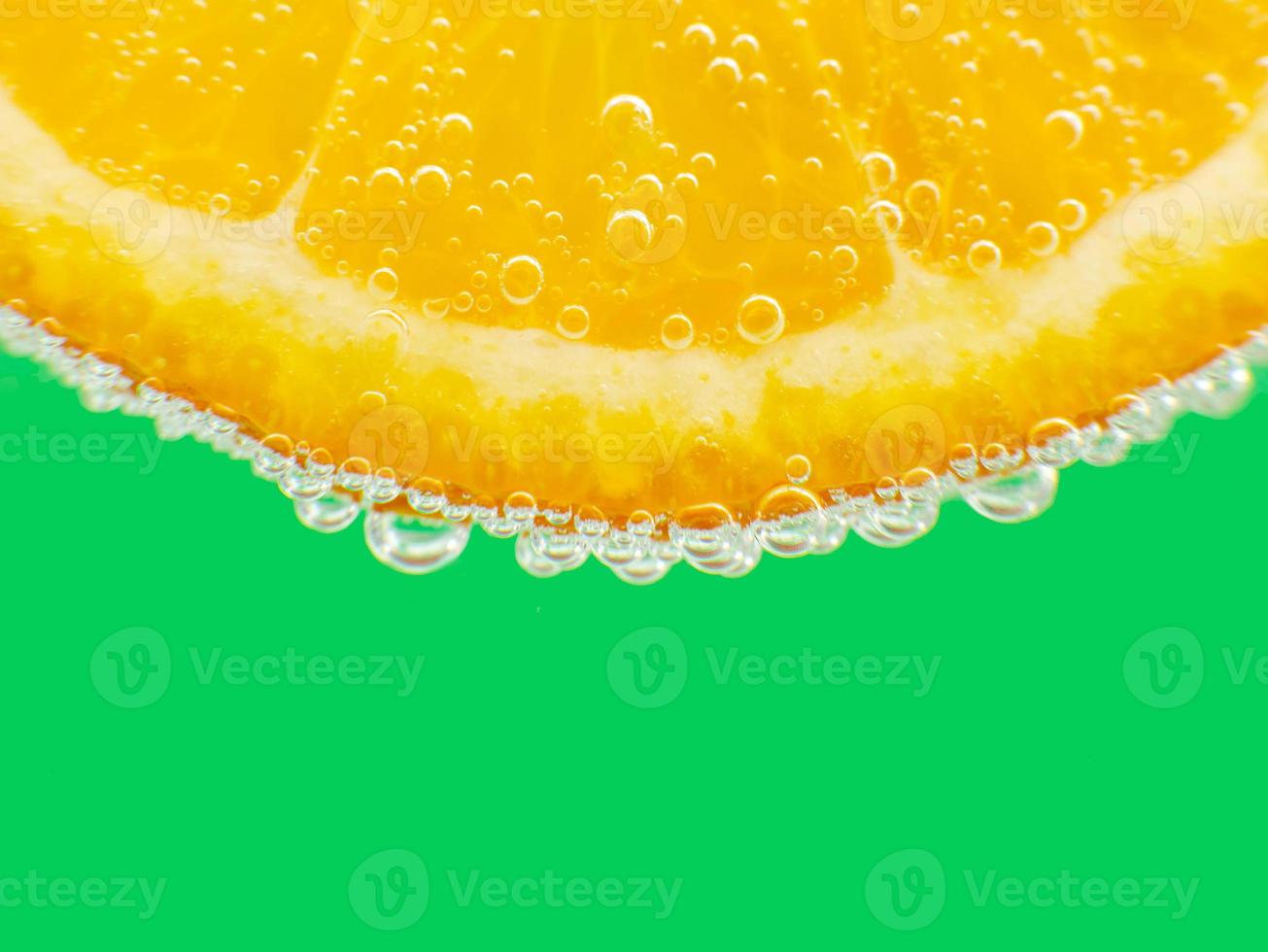 avvicinamento arancia nel scintillante acqua verde sfondo foto