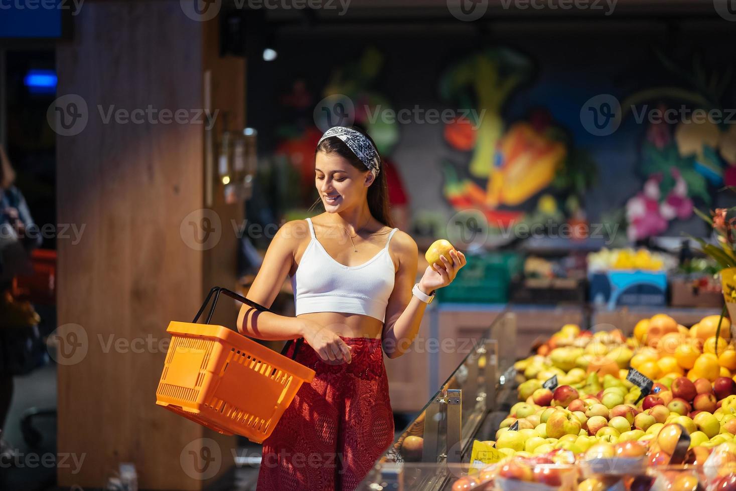 giovane donna fare shopping nel supermercato. la scelta mele nel memorizzare foto