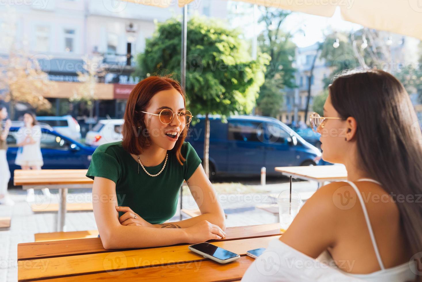 Due bella amiche parlando mentre seduta nel un' bar all'aperto foto