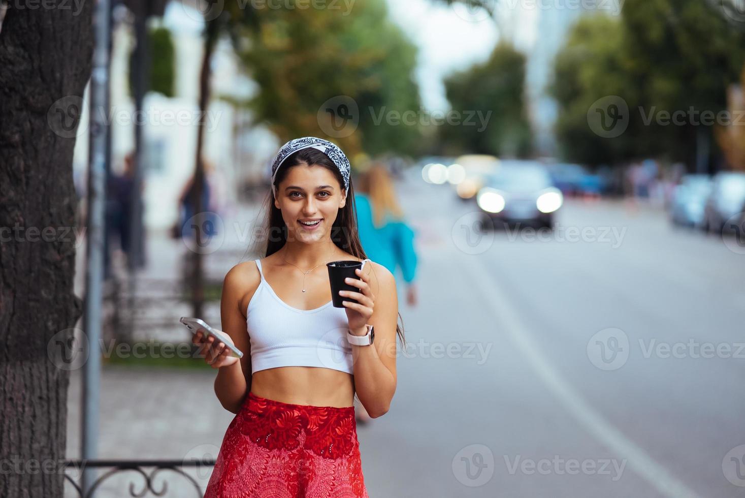 donna nel il strada potabile mattina caffè e uso smartphone. foto