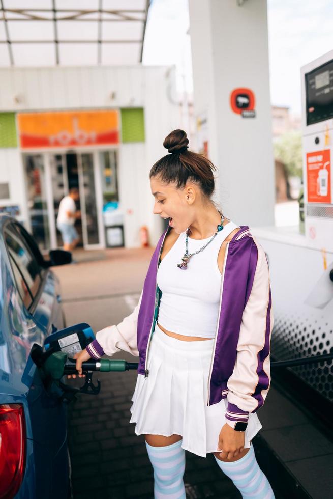 donna Riempimento sua auto con carburante a un' gas stazione foto