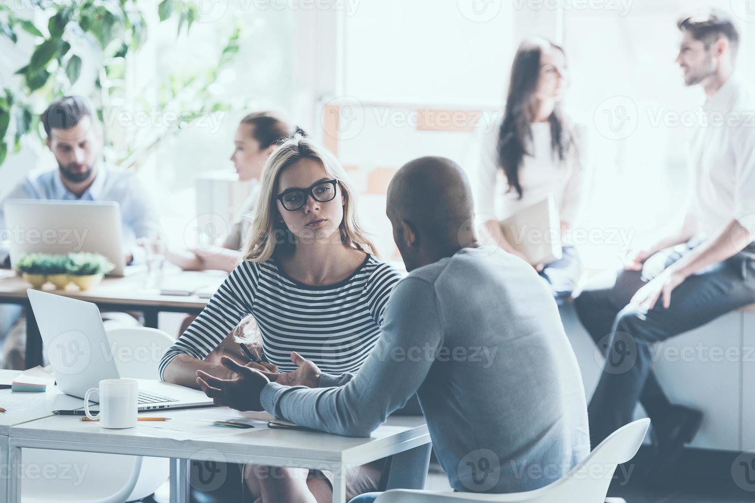 Lavorando momenti. gruppo di giovane attività commerciale persone Lavorando e comunicare con ogni altro mentre seduta a loro Lavorando posti nel ufficio foto