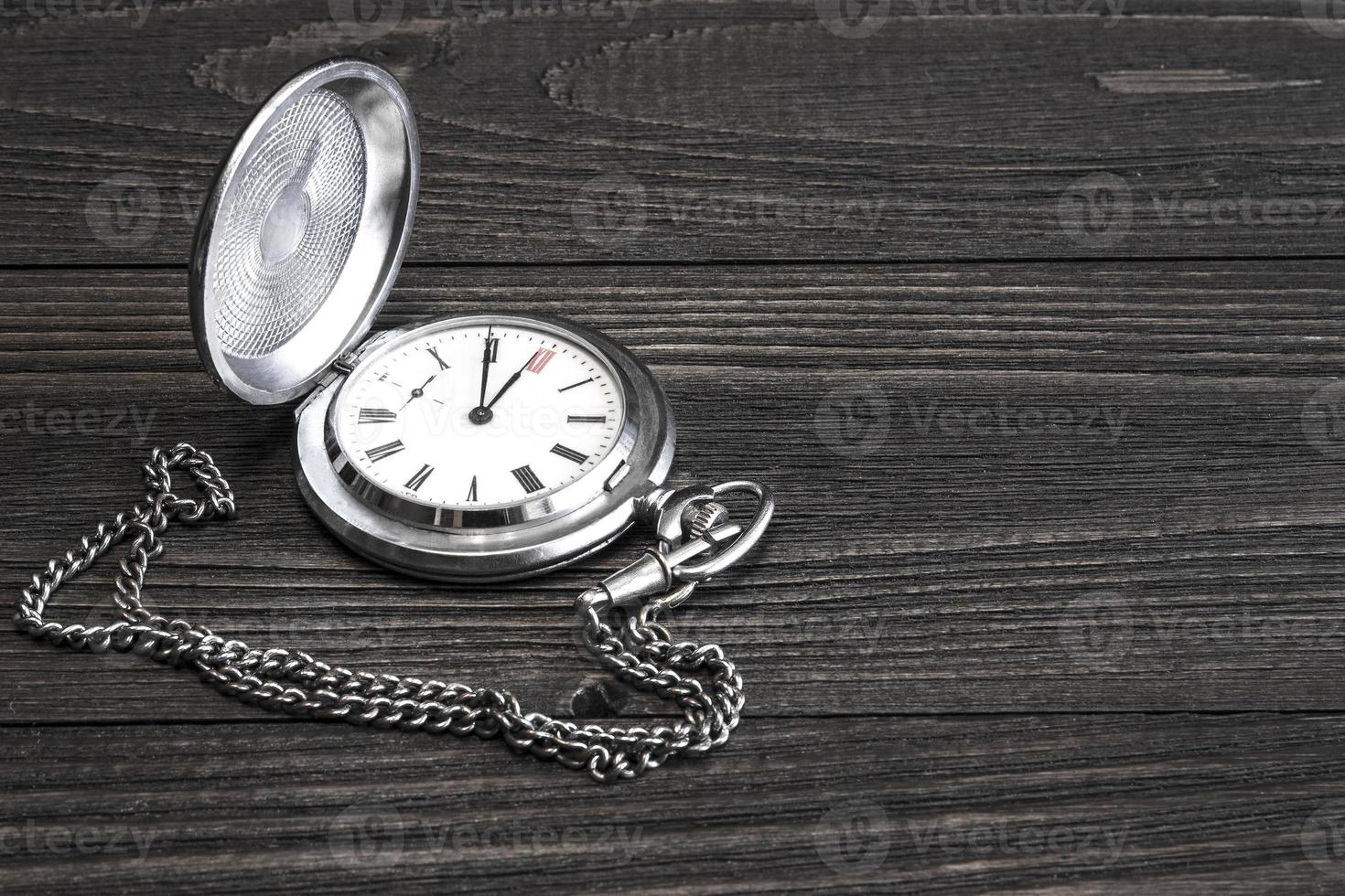 vecchio orologio da tasca con catena sdraiato su un tavolo di legno. foto
