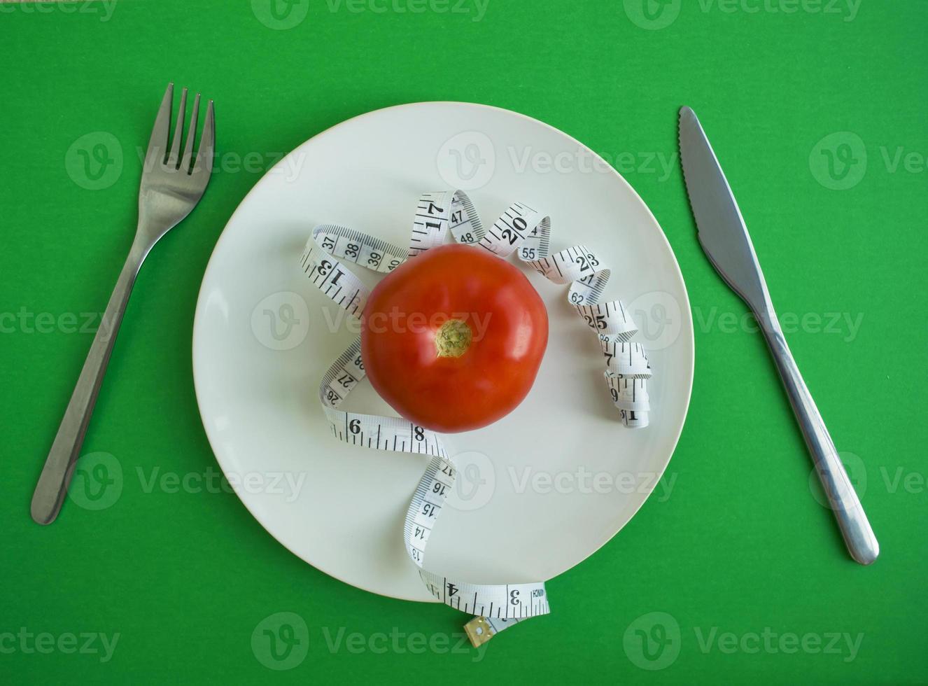 pomodoro e centimetro nastro nel un' piatto, forchetta e coltello foto