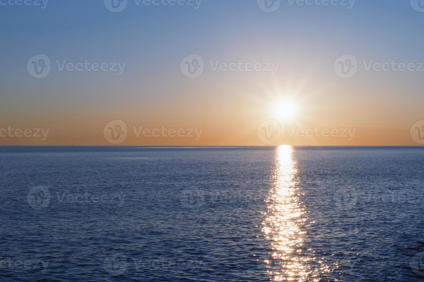 un' soleggiato tramonto su il mare allungamento in il orizzonte con un' sentiero e punti salienti su il mare. foto