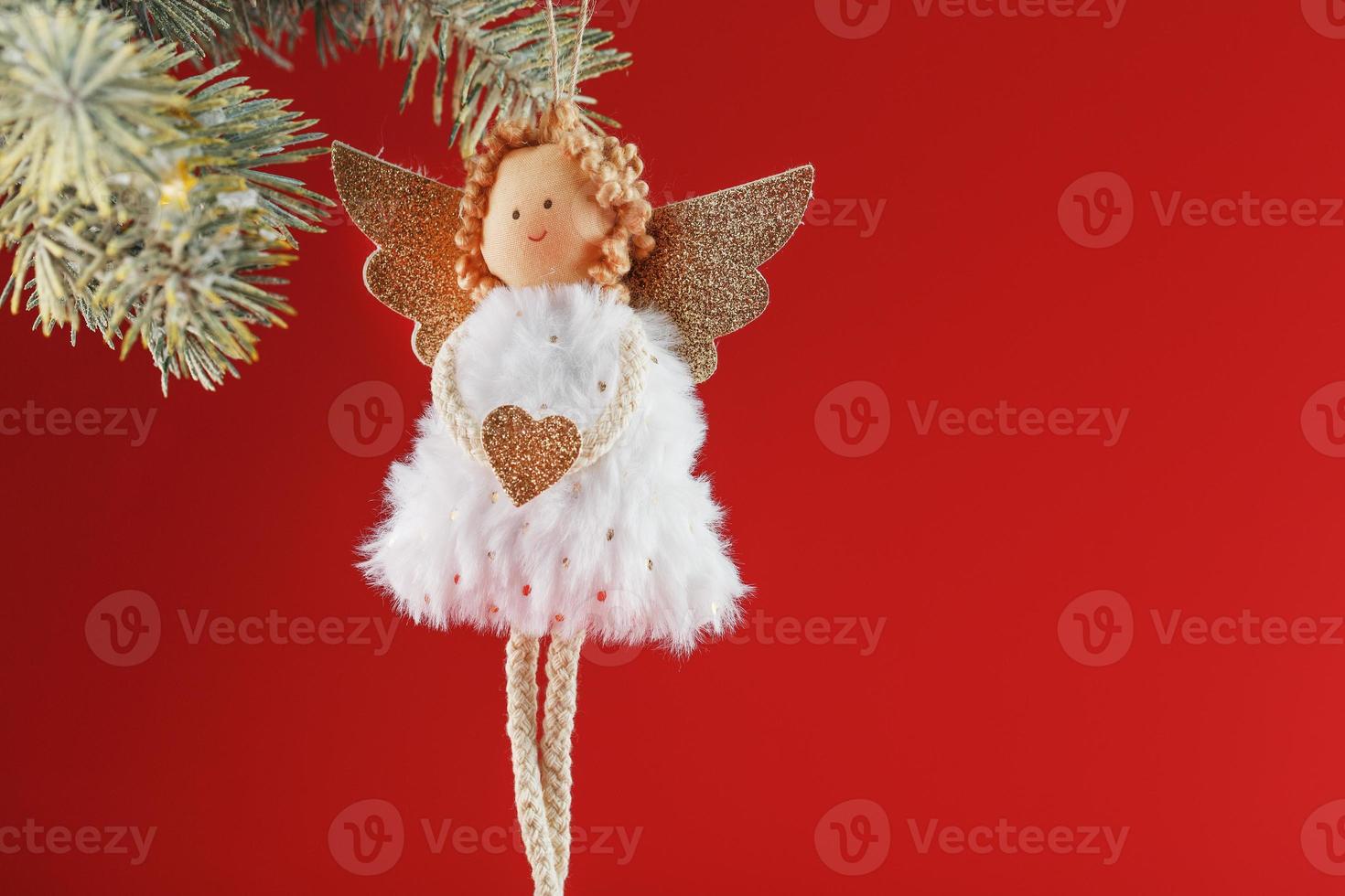fatto a mano Natale angelo giocattolo su un' Natale albero su un' rosso sfondo. foto