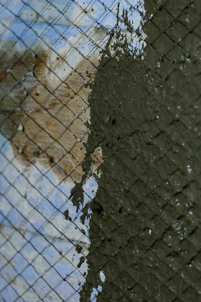 il maestro lanci un' soluzione di liquido calcestruzzo su il parete, il primo strato di gesso su il parete. foto