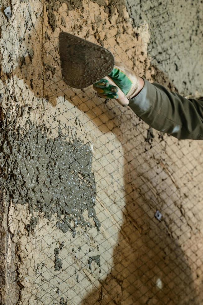 un' uomo lanci calcestruzzo mortaio su il parete, il primo strato di gesso su il parete, riparazione opera nel Ucraina. foto