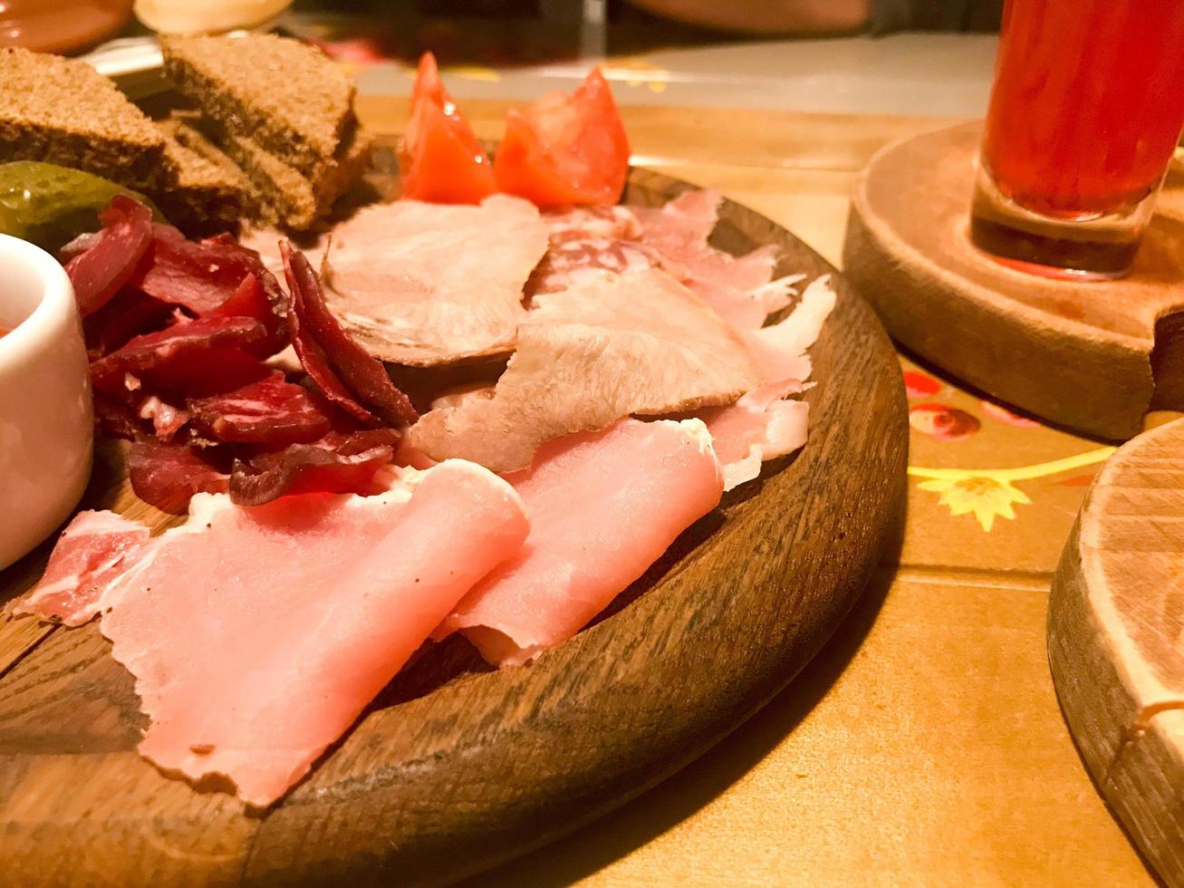 carne merenda con alcool a partire dal carne, prosciutto, basturm con salsa su di legno sta su il tavolo nel un' bar, sbarra, ristorante foto