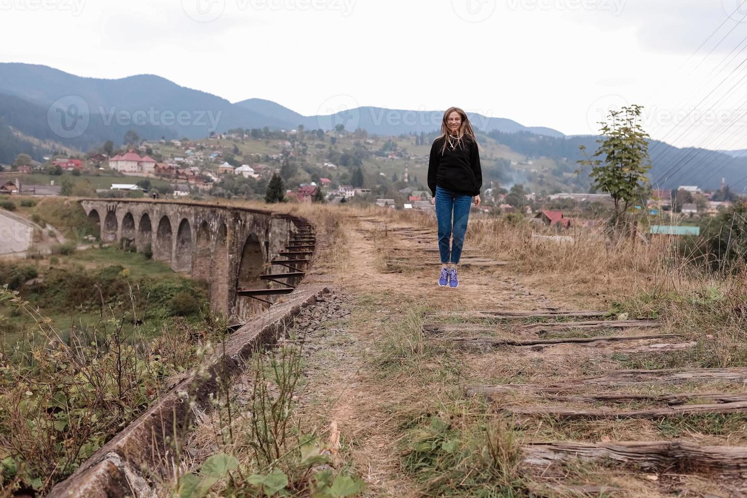 giovane turista ragazza passeggiate il vecchio ferrovia brani su il viadotto. vecchio ferrovia viadotto nel il montagna ricorrere villaggio di vorochta. Ucraina, Carpazi. foto