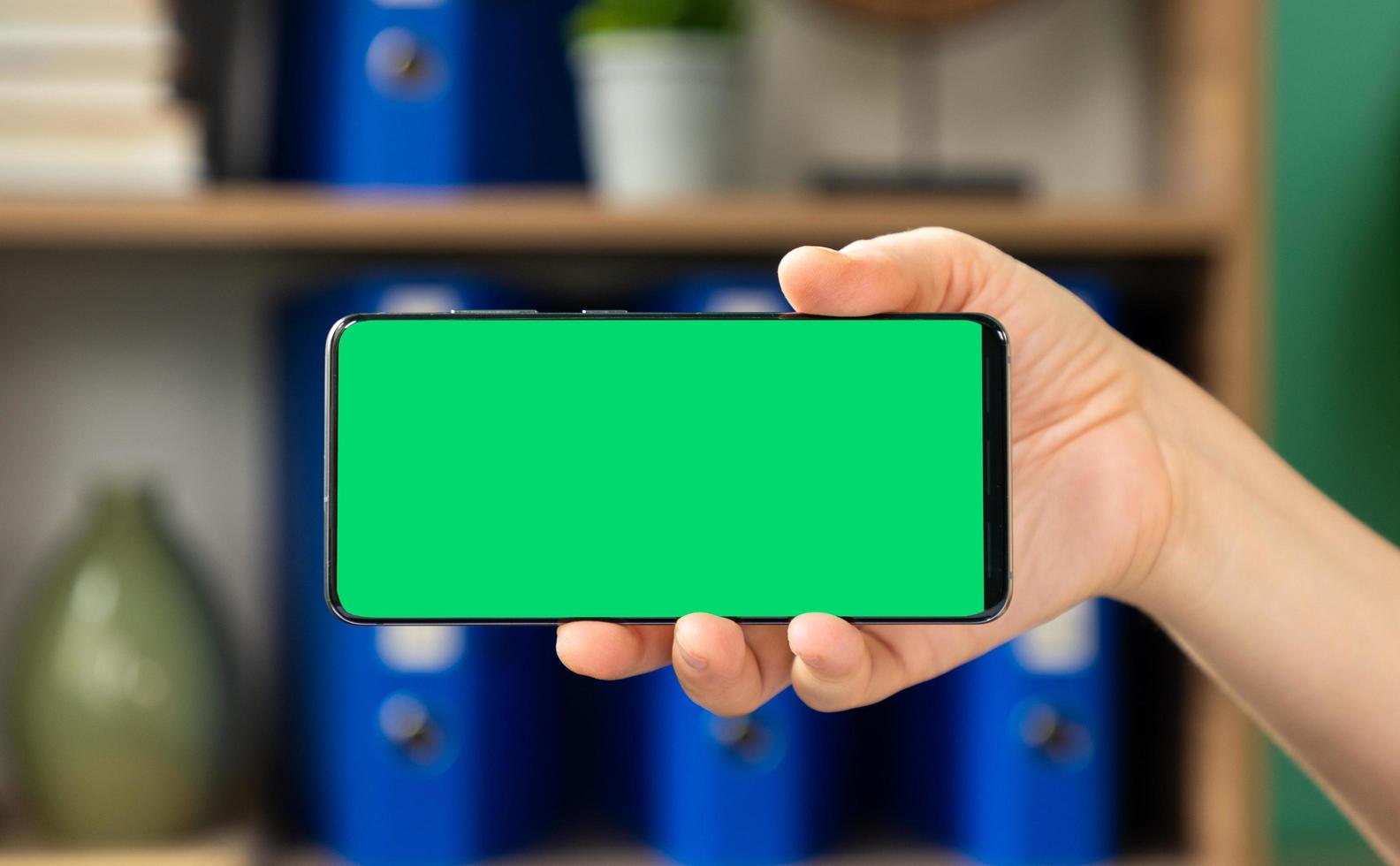 donna che tiene il telefono cellulare con schermo verde orizzontale foto