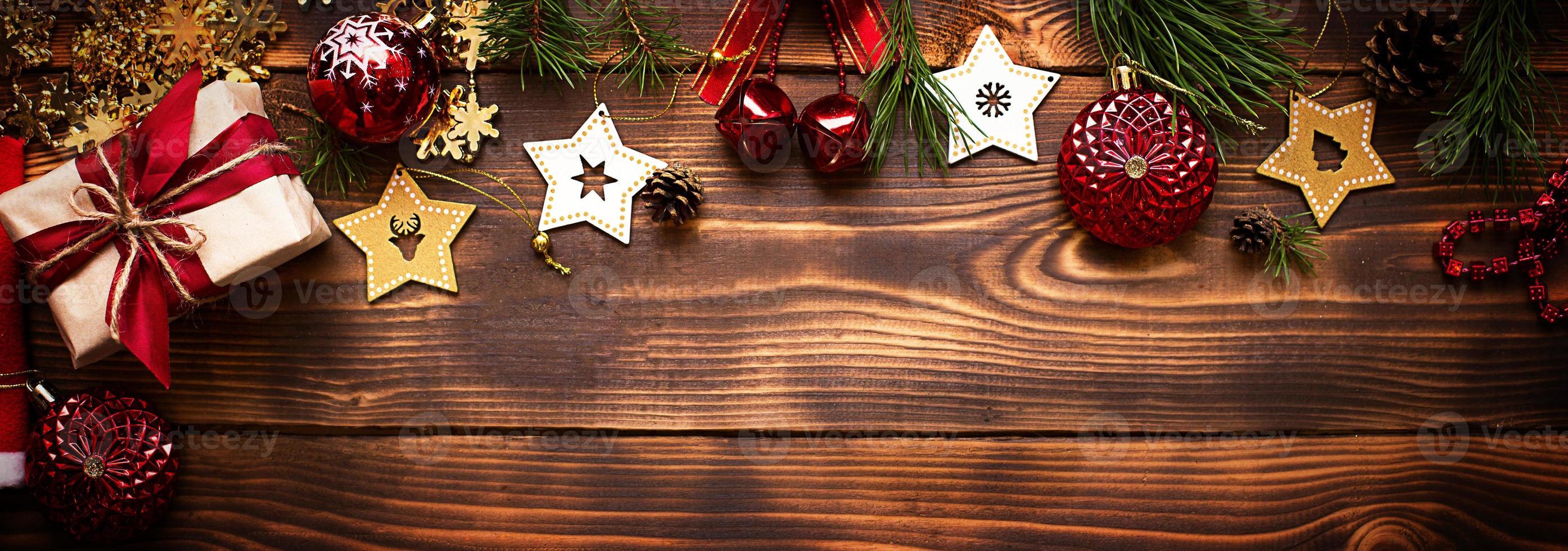 telaio con Natale arredamento su un' di legno sfondo. nuovo anno, vacanza atmosfera, verde abete rosso rami, decorazioni stelle, regalo scatola, perline, sfera, campane, coni. spazio per testo, piatto posare foto