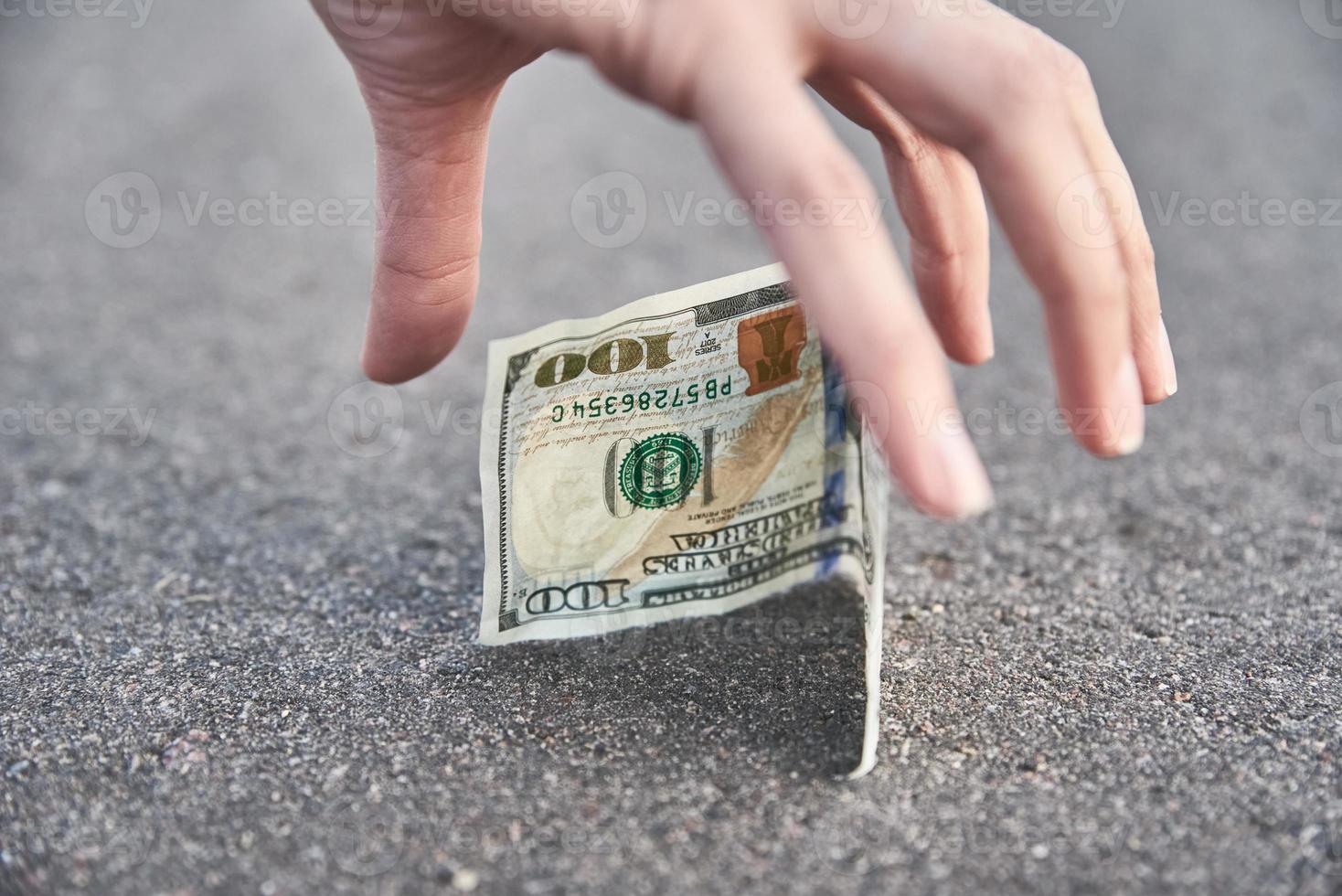 mano raccogliere uno centinaio dollaro banconota a partire dal terra. trovato i soldi concetto foto