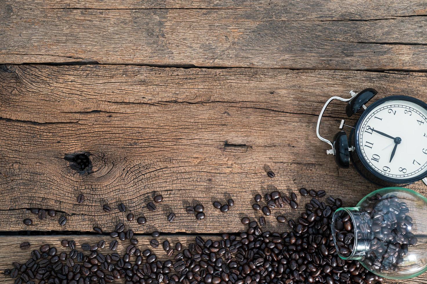 orologio e chicchi di caffè sulla scrivania foto