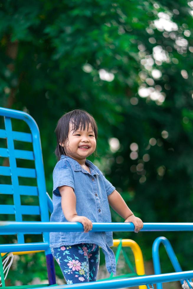 ragazza asiatica gode di giocare al parco giochi foto