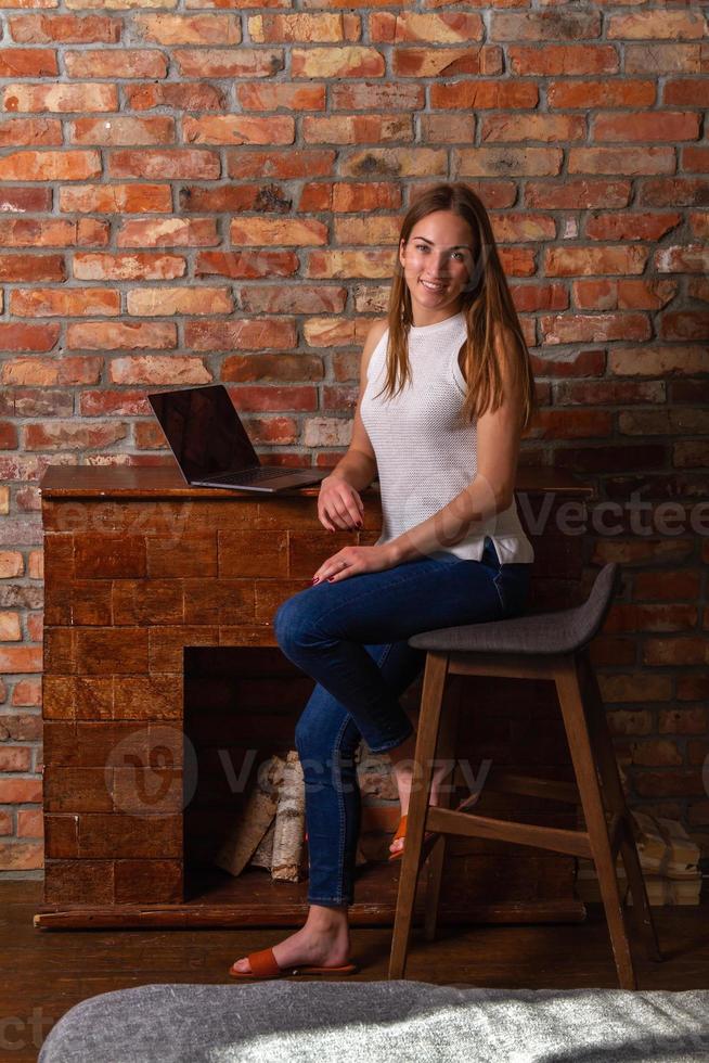 sorridente donna seduta su un' alto sedia con un' il computer portatile dietro a sua foto