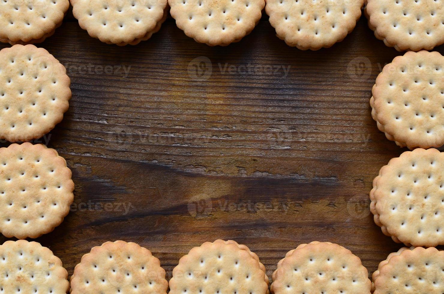 un' telaio di il giro biscotto Sandwich con Noce di cocco Riempimento su un' buio Marrone di legno superficie. insolito uso di biscotti come un' telaio. Immagine con copia spazio foto