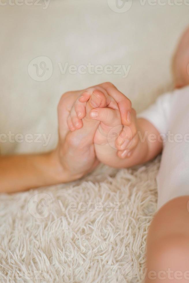 madre Tenere sua neonato bambino di poco mano, bambino si sente amore e sicurezza a partire dal madre foto