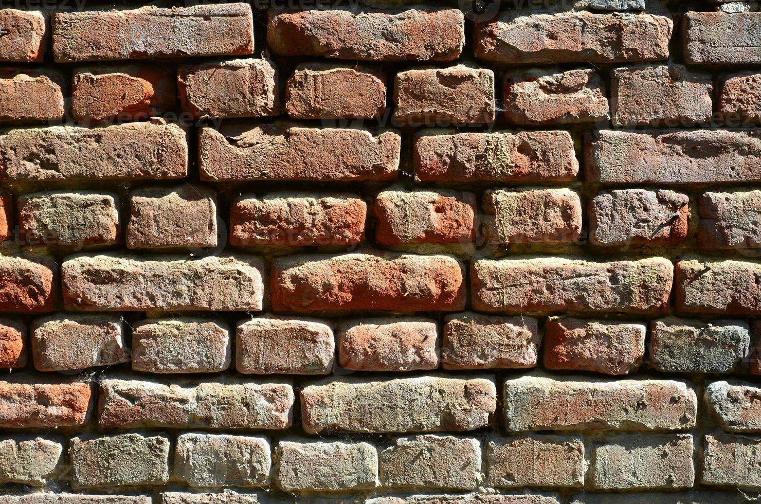 orizzontale parete struttura di parecchi righe di molto vecchio muratura fatto di rosso mattone. distrutto e danneggiato mattone parete con pizzicato angoli foto