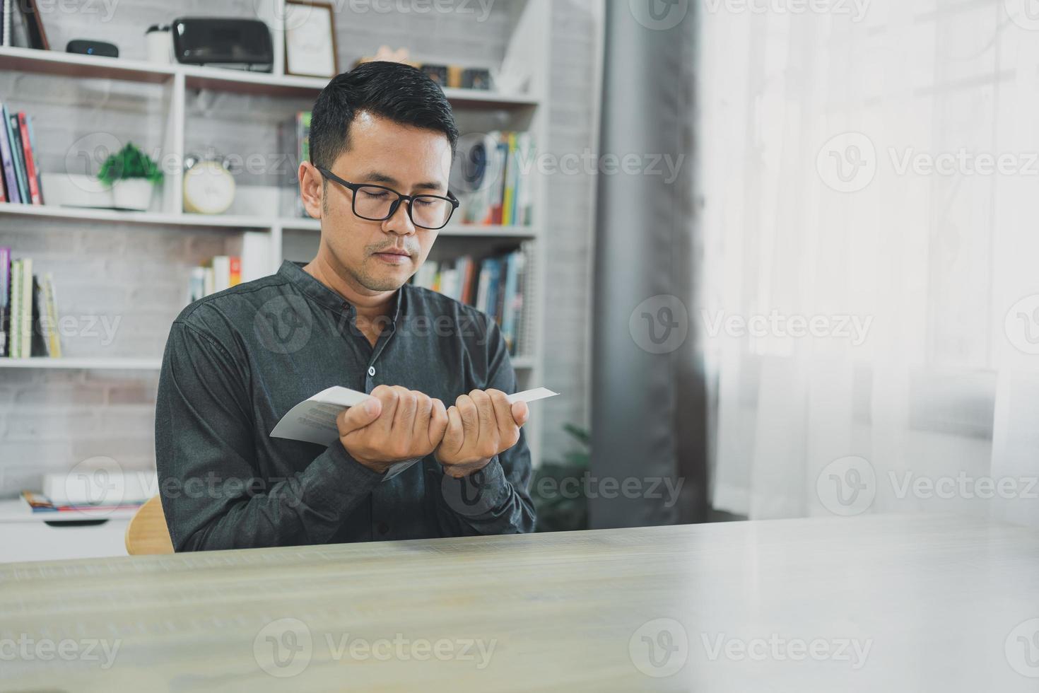 asiatico uomo fare mani insieme nel preghiera per Dio lungo con il Bibbia nel il cristiano concetto di fede, spiritualità e religione, uomini pregare nel il Bibbia. preghiera Bibbia nel il vivente camera a casa. foto