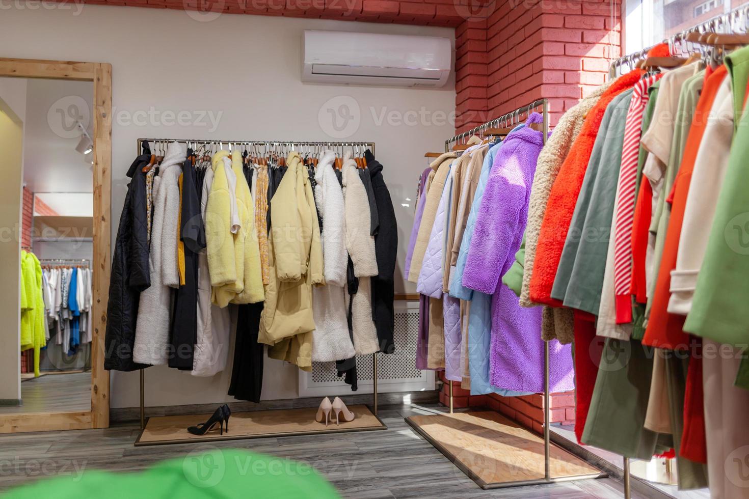 colorato Da donna vestiti, giacche, i pantaloni e altro Abiti su grucce nel un' Al dettaglio negozio. il concetto di moda e acquisti. Da donna capi di abbigliamento boutique. foto