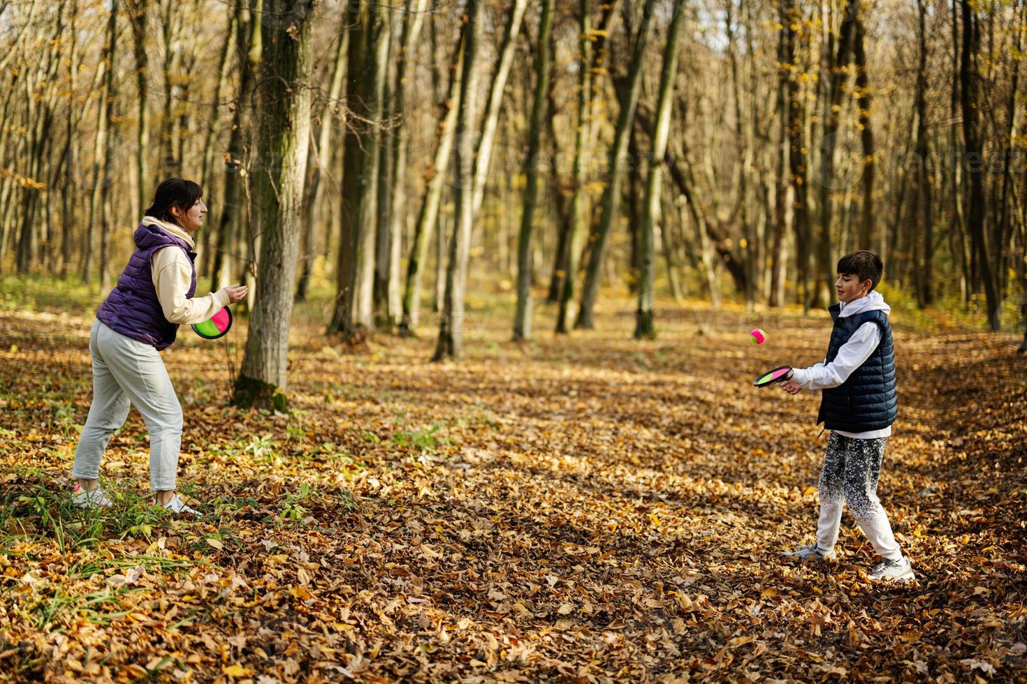 madre con figlio giocare nel autunno foresta catturare e lanciare palla gioco. foto