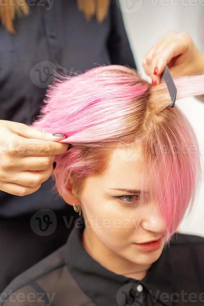 parrucchiere rettilinei rosa capelli di donna di capelli ferro da stiro. foto